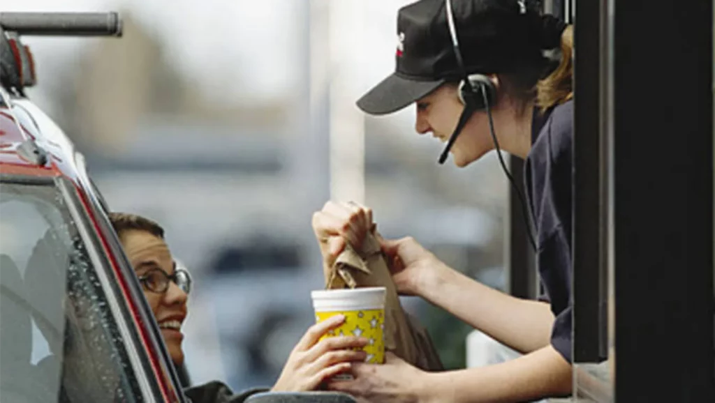 Photo of empolyee serving a customer through a fast food drive through window